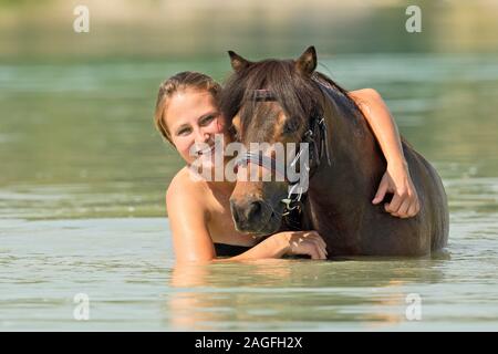 Jeune femme et d'un poney Shetland miniature dans un lac Banque D'Images