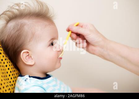 Manger une cuillère de bébé mange de la bouillie de lait Banque D'Images