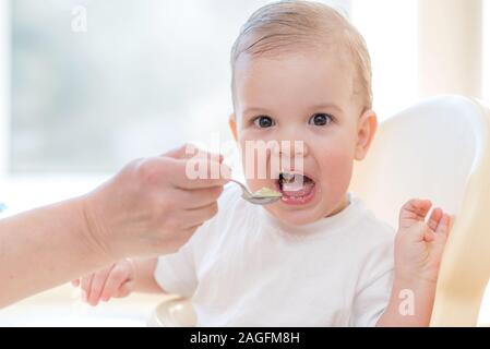 Manger une cuillère de bébé mange de la bouillie de lait Banque D'Images