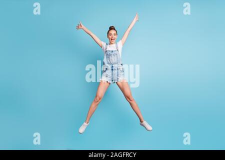 La taille du corps sur toute la longueur de la photo fascinante de charme bénéficiant d'étirement fille positive, tandis que seul avec fond bleu Banque D'Images