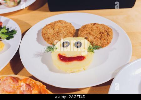 L'alimentation de l'enfant. Drôle de nourriture. La plaque avec les escalopes et sa purée de pommes de terre sous la forme d'un singe est confrontée. Menu enfants Banque D'Images