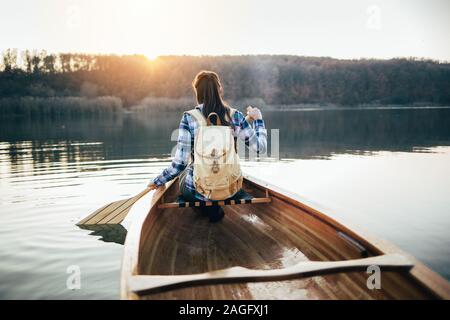 Vue arrière du canot sur la femme sunset lake Banque D'Images