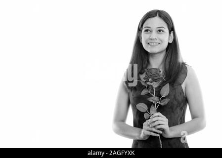 Thoughtful young woman smiling and holding red rose prêt pour la Saint-Valentin Banque D'Images