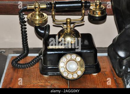 Une ligne téléphonique directe rétro noir n'est pas oxydée sur une terrasse en bois de couleur d'or chaud. Banque D'Images