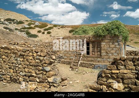 Petite maison de nouvelle construction avec les aliments pour bétail sur le toit entourée de murs en pierre sèche dans l'Himalaya de village isolé, Tashigang Himachal Pradesh, Inde. Banque D'Images