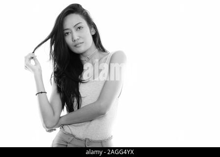 Studio shot of young beautiful Asian woman touching her hair Banque D'Images