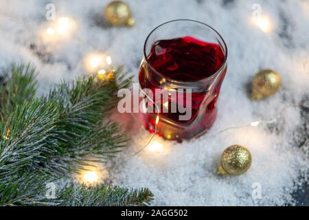 En verre transparent avec une boisson festive. Vin chaud ou compote. Se trouve dans la neige artificielle. Près d'une succursale de l'épinette. Noël et Nouvel An. Spa de copie Banque D'Images