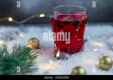 En verre transparent avec une boisson festive. Vin chaud ou compote. Se trouve dans la neige artificielle. Près d'une succursale de l'épinette. Noël et Nouvel An. Spa de copie Banque D'Images