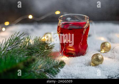 En verre transparent avec une boisson festive. Vin chaud ou compote. Se trouve dans la neige artificielle. Près d'une succursale de l'épinette. Noël et Nouvel An. Spa de copie Banque D'Images