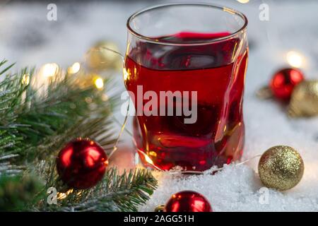 En verre transparent avec une boisson festive. Vin chaud ou compote. Se trouve dans la neige artificielle. Près d'une succursale de l'épinette. Noël et Nouvel An. Spa de copie Banque D'Images