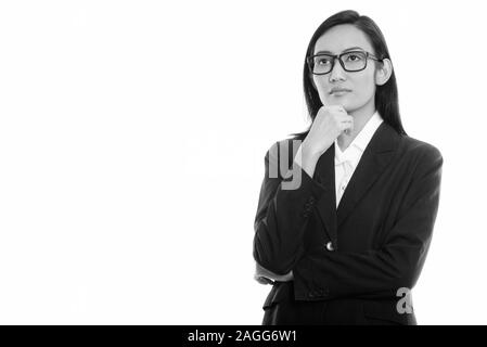 Studio shot of young Asian businesswoman wearing eyeglasses en pensant Banque D'Images