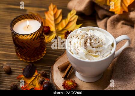 La tasse de café chaud avec de la crème et d'épices cannelle, chocolat chaud automne cadre confortable avec douce couverture et bougies Banque D'Images