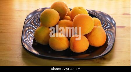 Les abricots sur un plat laqué noir sur la table Banque D'Images