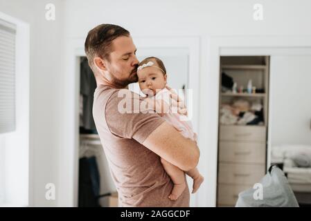 Père réconfortant baby girl d'armes à la maison Banque D'Images