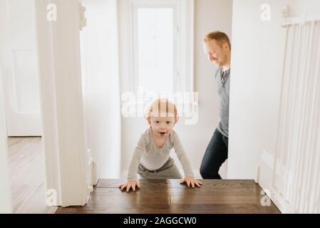 Suite père fils ramper jusqu'escalier dans chambre Banque D'Images