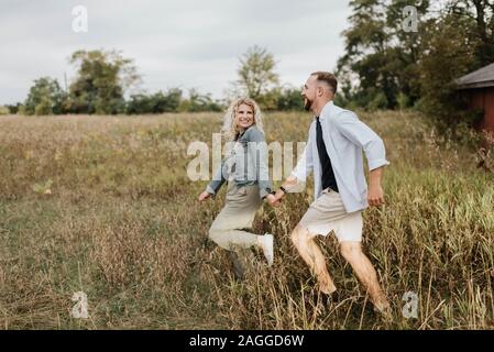 Jeune couple sautant dans la campagne Banque D'Images