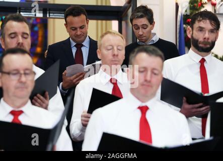 Taoiseach Leo Varadkar (arrière gauche) et ministre de la santé Simon Harris (arrière droite) rejoindre la chorale du personnel du Ministère pour leur déjeuner annuel considérant de chants de Noël au gouvernement Bâtiments dans Dublin. Banque D'Images