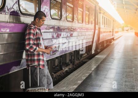 Voyageur avec bagages et tablette numérique en gare. Concept de voyage. Banque D'Images