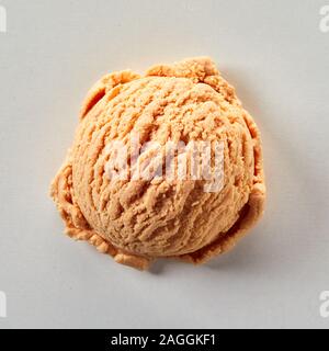 Seule boule de yogourt glacé aromatisé au caramel ou glace Vue de haut en bas sur un fond blanc dans un gros plan sur la texture Banque D'Images