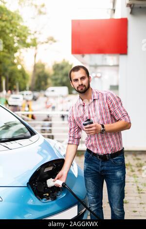 Jeune homme charger sa voiture et boire du café Banque D'Images