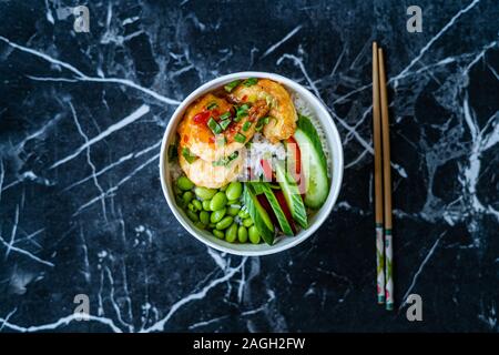 Emporter le Bouddha sain bol avec crevettes, Edamame Beans, concombre et Riz Basmati / Bol Poke dans un coffret plastique emballage ou contenant. La nourriture traditionnelle. Banque D'Images