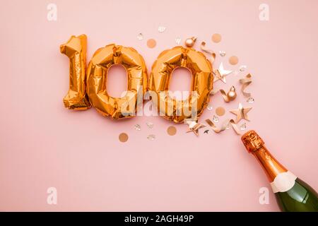 Heureux 100e anniversaire partie. Bouteille de champagne avec de l'or nombre ballon. Banque D'Images