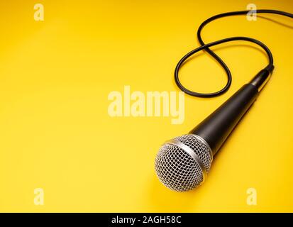 Microphone avec câble bouclés sur fond jaune Banque D'Images