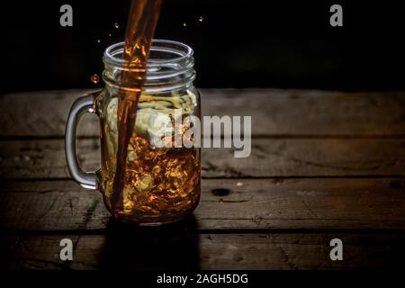 Gros plan d'un pot rempli d'un froid boire de l'alcool lorsqu'il est placé sur une surface en bois Banque D'Images