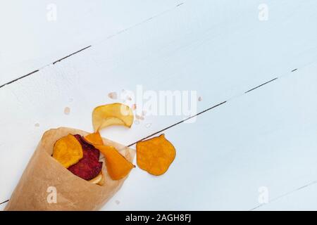 Chips de légumes mélangés à la main avec du sel de mer chevronnés sur table en bois blanc Banque D'Images