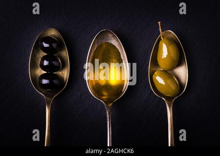 Sur l'ardoise trois cuillerées à soupe, un plein d'huile d'olive extra vierge et les autres avec des olives vertes et noires Banque D'Images