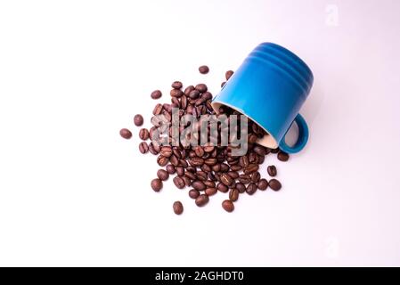 Café en grains déversés par un mug isolé sur fond blanc Banque D'Images