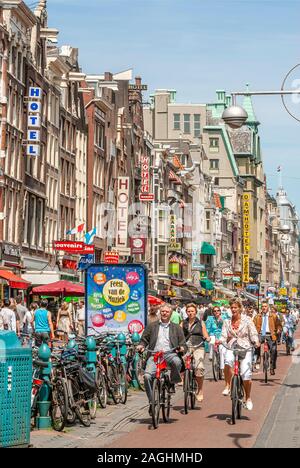Cycliste au Damrak Rue commerçante dans le centre-ville d'Amsterdam Banque D'Images