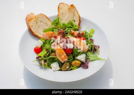 Tout petits calamars sur un plateau dans une salade décorée avec des olives, des morceaux de tomates et de pain au fromage blanc Banque D'Images