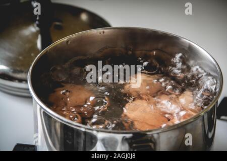 Les oeufs bruns bouillir dans une petite casserole sur la cuisinière Banque D'Images