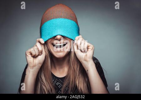 Portrait d'une femme souriante portant un chapeau sur son visage, le jeu et le plaisir, notion de profiter de la vie, les jeunes de la mode funky Banque D'Images