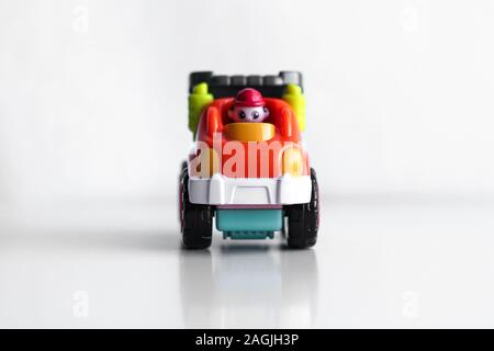 Camion benne jouet en plastique du véhicule de construction isolé sur fond blanc avec la réflexion. Vue avant de la benne. Véhicule Orange avec roues rouges et le nom du texte. Dans l'opérateur red hard hat Banque D'Images