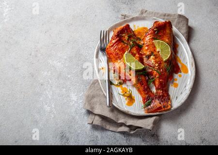 Loup de mer rouge au four sur la plaque de béton blanc kraft, arrière-plan. Banque D'Images