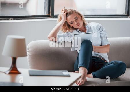Somnolence et fatigue. Businesswoman avec cheveux blonds siégeant à la salle la fenêtre contre Banque D'Images