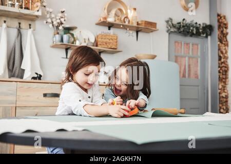 Enfance heureuse. Deux enfants jouant avec des jouets de couleur jaune et orange dans la cuisine blanche Banque D'Images