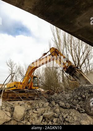 Low angle view of a yellow exécutant une Pelle de démolition de béton armé avec un marteau hydraulique. Construction site Banque D'Images