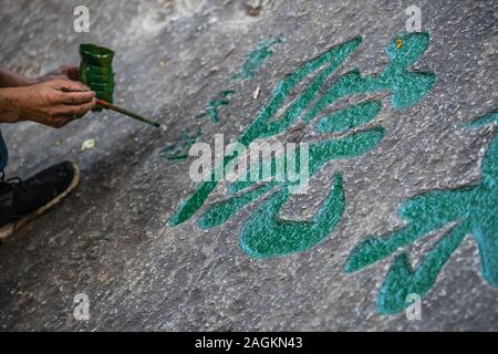 Huashan, Chine - Août 2019 : Man painting calligraphie chinoise caractères sur un gros rocher dans la cour d'un temple bouddhiste au pied de l'Hu Banque D'Images