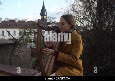 Portrait d'une jeune femme (20-24 ans) harpiste jouant sa harpe à l'extérieur du Château de Prague. Partie d'une série. Prague, République tchèque. 2019. Copyspace. Banque D'Images