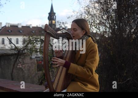 Portrait d'une jeune femme (20-24 ans) harpiste jouant sa harpe à l'extérieur du Château de Prague. Partie d'une série. Prague, République tchèque. 2019. Copyspace. Banque D'Images