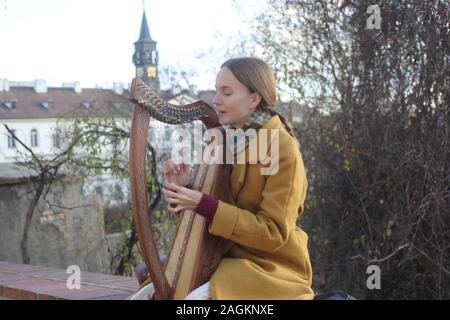 Portrait d'une jeune femme (20-24 ans) harpiste jouant sa harpe à l'extérieur du Château de Prague. Partie d'une série. Prague, République tchèque. 2019. Copyspace. Banque D'Images