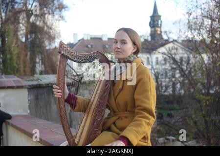 Portrait d'une jeune femme (20-24 ans) harpiste jouant sa harpe à l'extérieur du Château de Prague. Partie d'une série. Prague, République tchèque. 2019. Copyspace. Banque D'Images