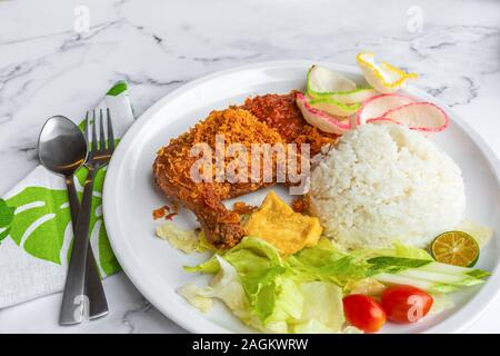 Penyet Ayam est une cuisine de l'Est javanais indonésien - composé de poulet frit, c'est écrasé au pilon Mortier contre pour l'assouplir, servi Banque D'Images