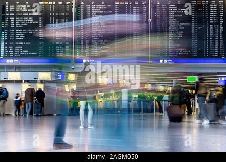 20 décembre 2019, Hessen, Frankfurt/Main : Les passagers passent devant l'écran de sélection dans le Terminal 1 de l'aéroport. Une augmentation du nombre de passagers est attendue dans les prochains jours. Photo : Boris Roessler/dpa Banque D'Images