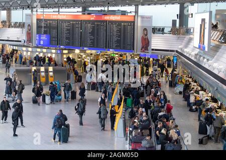 20 décembre 2019, Hessen, Frankfurt/Main : Les passagers attendent leur arrivée au comptoir d'en dessous de l'écran de sélection dans le Terminal 1 de l'aéroport. Une augmentation du nombre de passagers est attendue dans les prochains jours. Photo : Boris Roessler/dpa Banque D'Images