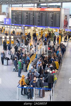 20 décembre 2019, Hessen, Frankfurt/Main : Les passagers attendent leur arrivée au comptoir d'en dessous de l'écran de sélection dans le Terminal 1 de l'aéroport. Une augmentation du nombre de passagers est attendue dans les prochains jours. Photo : Boris Roessler/dpa Banque D'Images