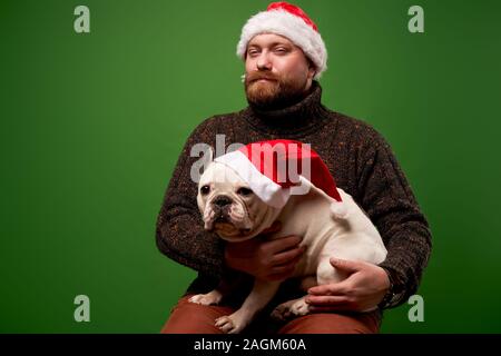 Un homme et chien dans santa caps sur fond vert en studio vide Banque D'Images